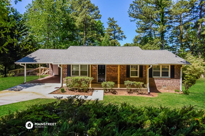 a small brick house with a lawn and trees