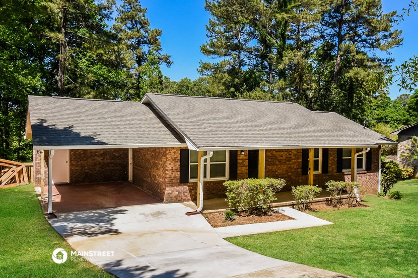 a small brick house with a porch and a driveway
