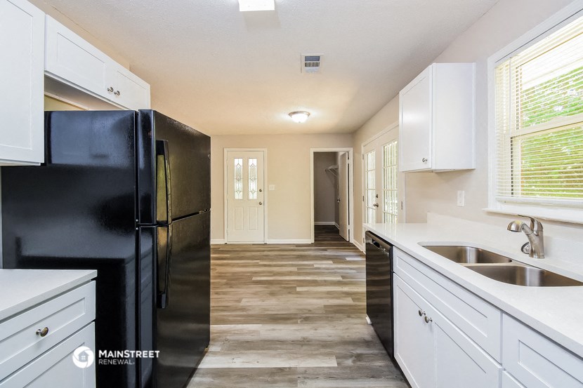 a kitchen with white cabinets and a black refrigerator