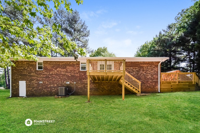 a backyard with a deck and a brick house with a wooden deck
