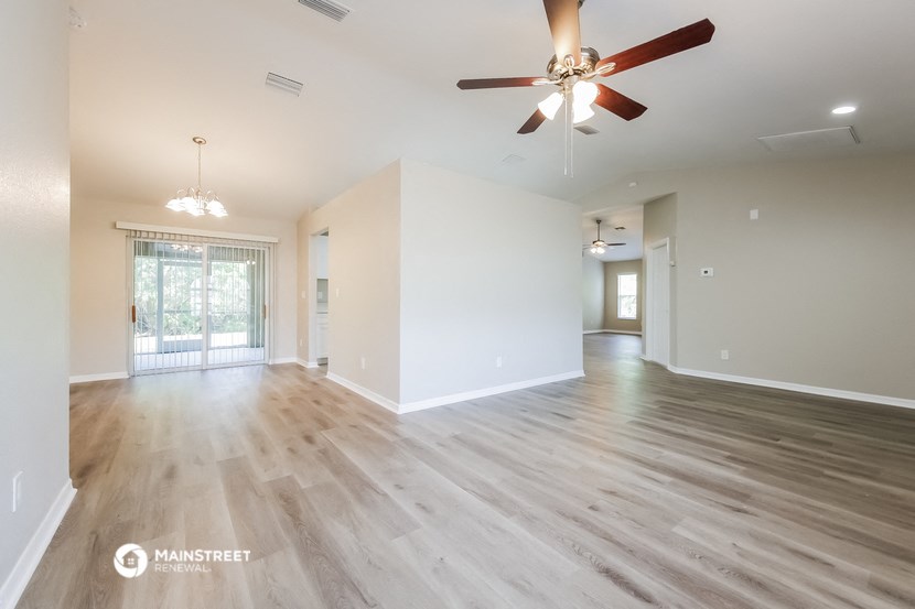 the spacious living room and dining room with wood flooring and ceiling fan