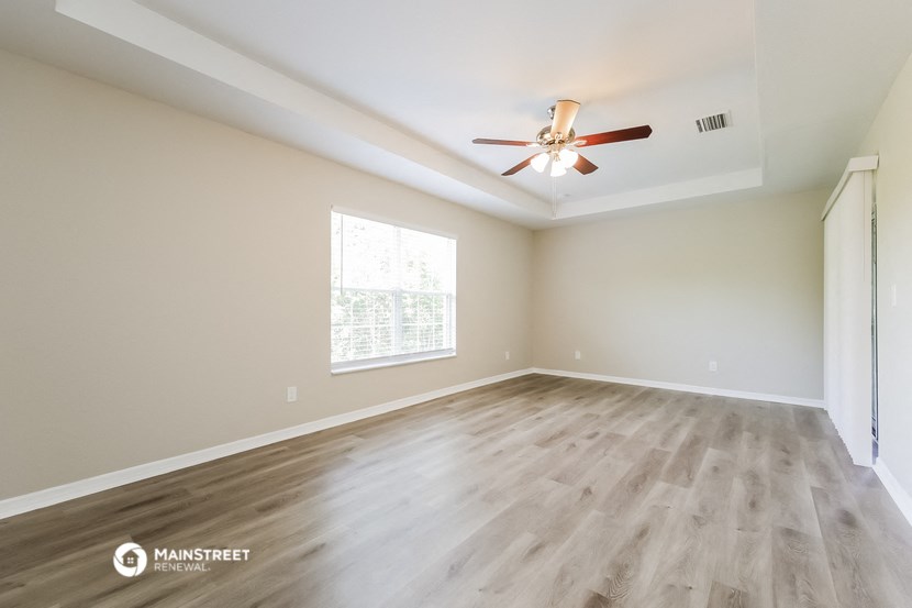 the spacious living room with hardwood floors and a ceiling fan