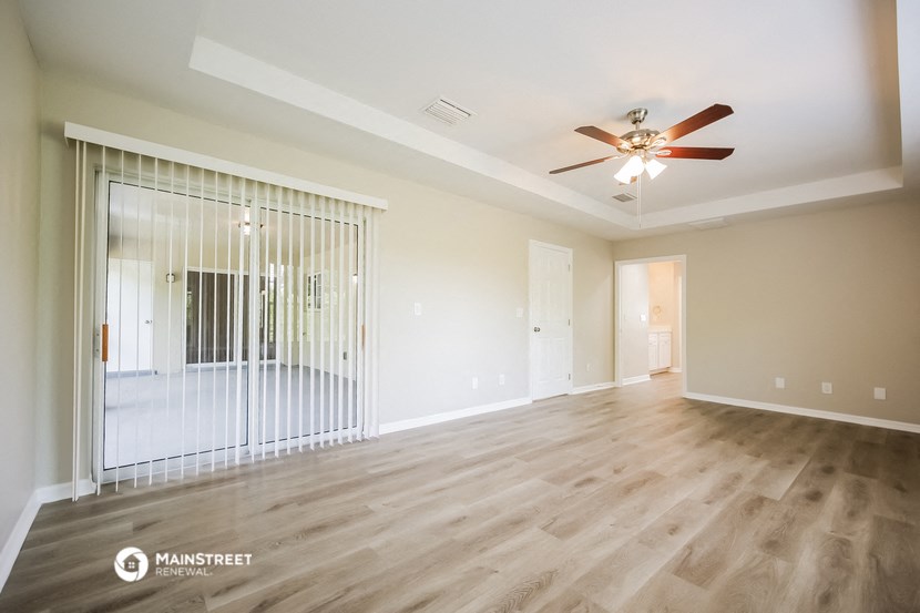 an empty living room with a ceiling fan and a window