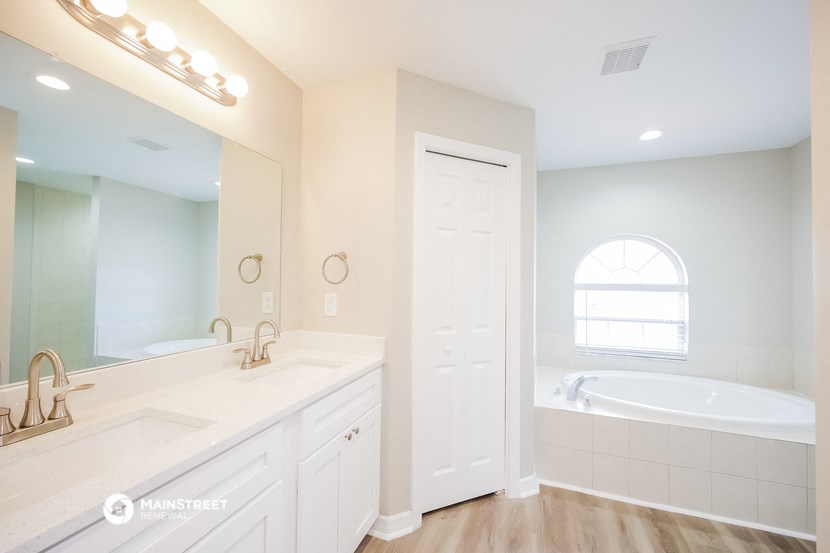 a white bathroom with a tub and a sink and a mirror