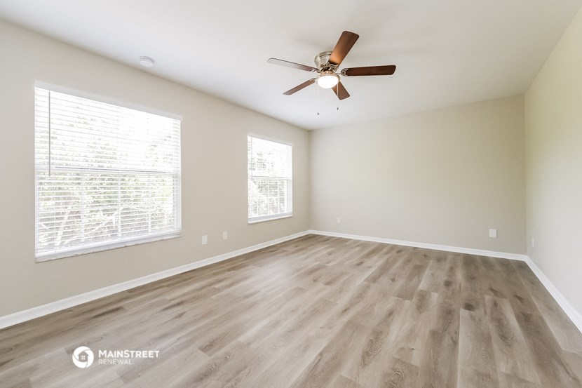 an empty living room with wood floors and a ceiling fan