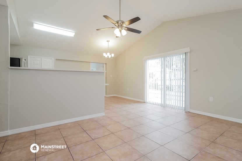 an empty living room with a ceiling fan and a sliding glass door