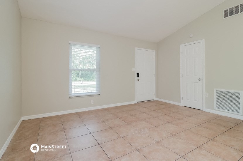 an empty living room with a tiled floor and a white door