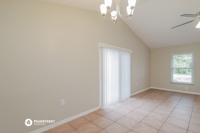 a empty living room with a ceiling fan and a window