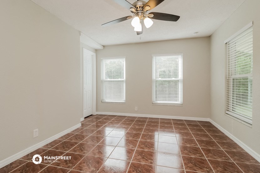 a empty living room with a ceiling fan and two windows