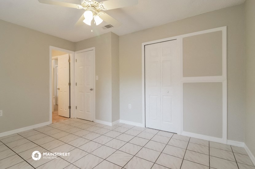 an empty living room with white doors and a tile floor