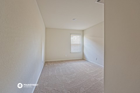 the living room of an apartment with carpet and a window