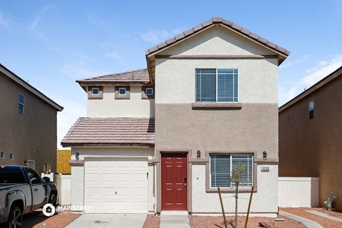 a beige house with a red door and white garage doors