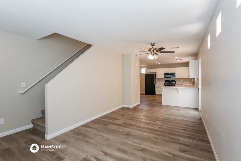 a renovated living room and kitchen with a ceiling fan