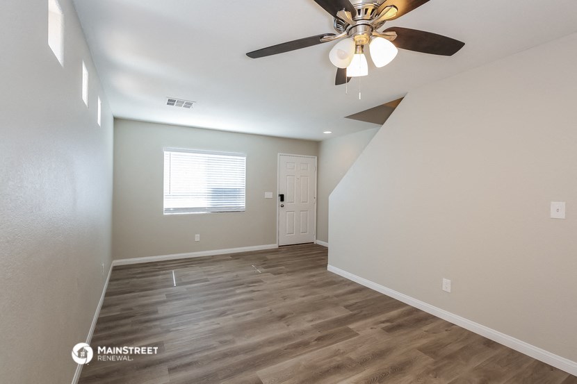 the spacious living room with ceiling fan and hardwood floors