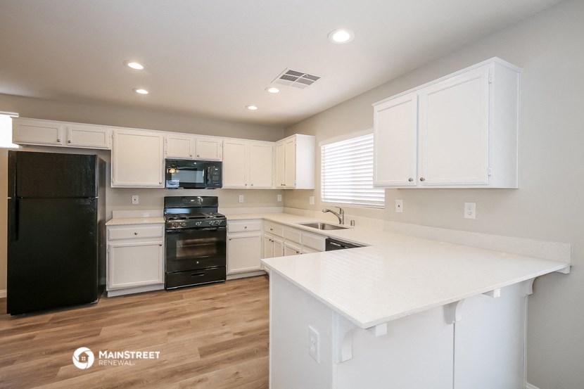 a white kitchen with black appliances and white counter tops