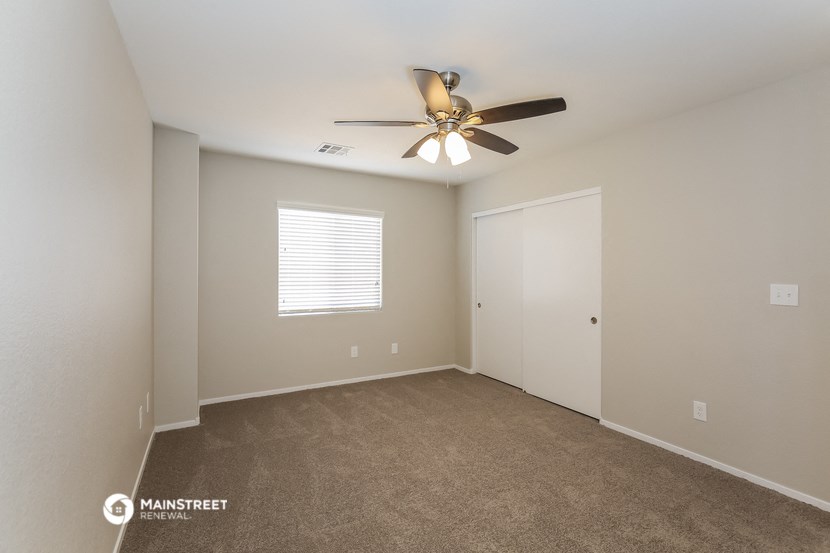 the spacious living room with ceiling fan and carpet