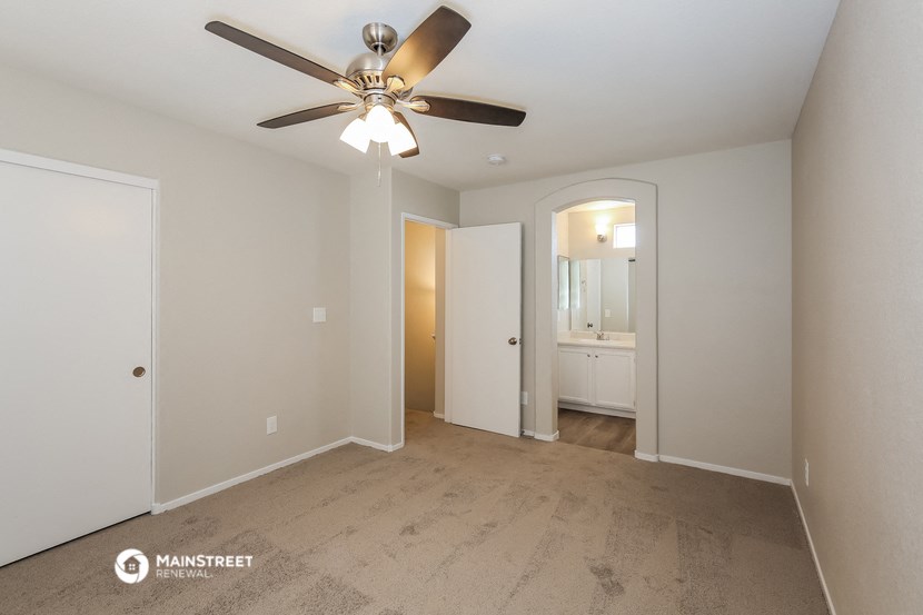 a living room with a ceiling fan and a door to a bathroom