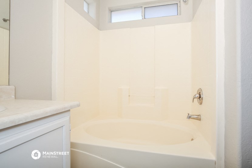 a bathroom with a tub and a sink and a window
