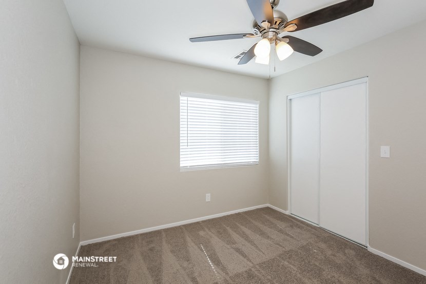 the living room of a manufactured home with a ceiling fan and a closet
