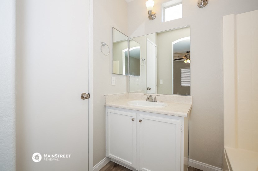 a bathroom with white cabinets and a sink and a mirror