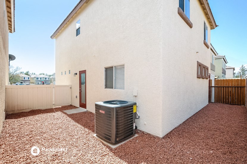 a side view of a white house with a heater in the yard