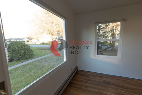 A room with a window showing a view of a lawn and trees.