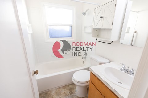 A bathroom with Rodman Realty Inc. logo on the wall.
