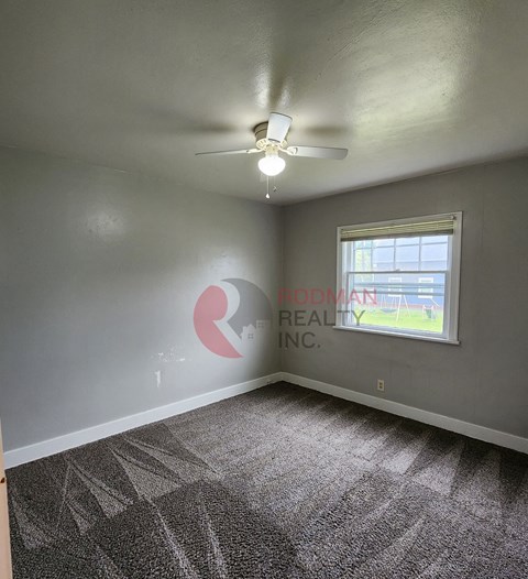 A room with a carpeted floor and a ceiling fan.