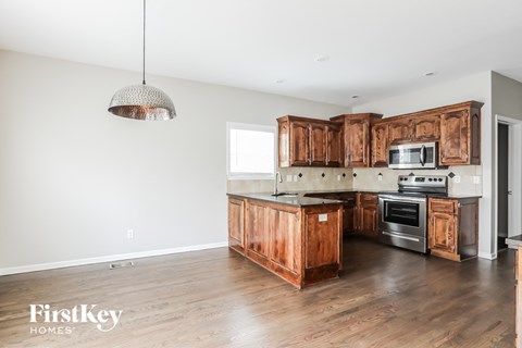 A kitchen with wooden cabinets and a hanging light fixture.