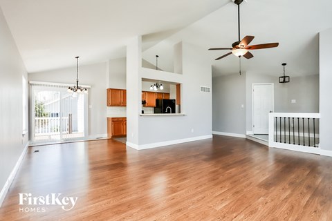 an empty living room with wood floors and a ceiling fan