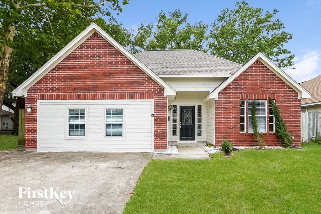 a white and red brick house with a driveway and grass