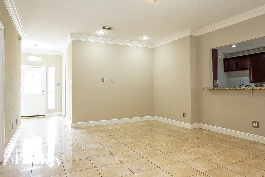 an empty living room with tiled floors and a kitchen