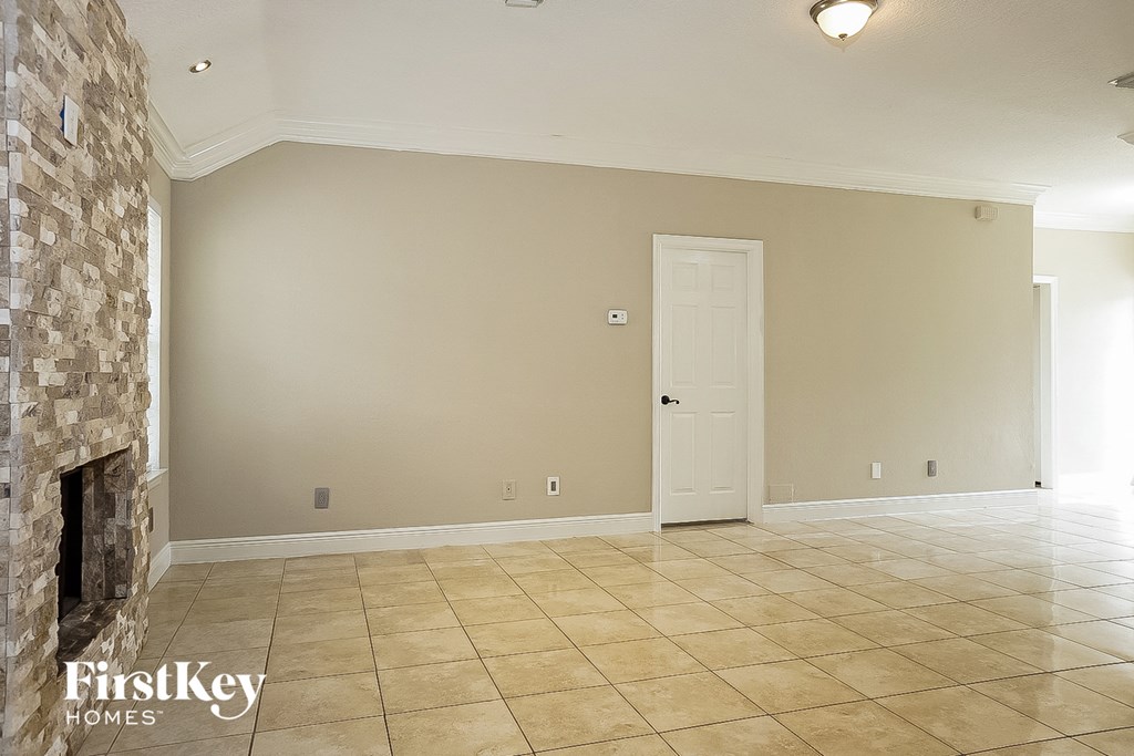 an empty living room with a fireplace and tile flooring