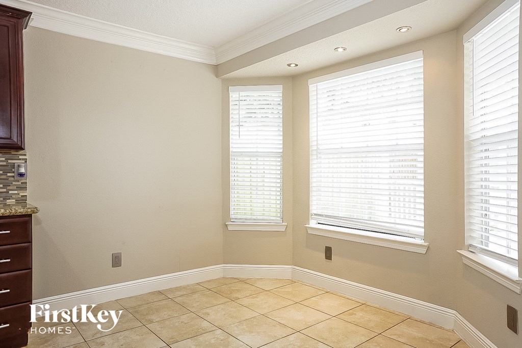 a dining room with three windows and a tiled floor