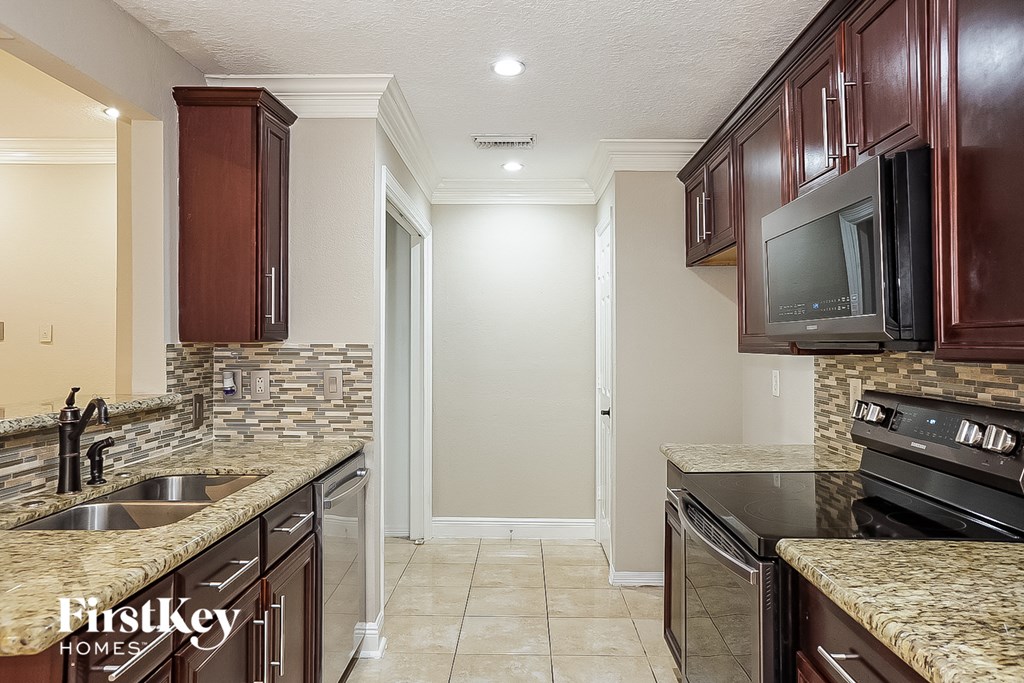 a kitchen with a sink and a stove and a tv