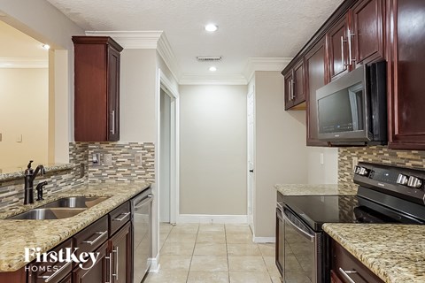 a kitchen with a sink and a stove and a tv