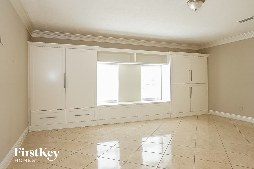 an empty living room with white cabinets and a window