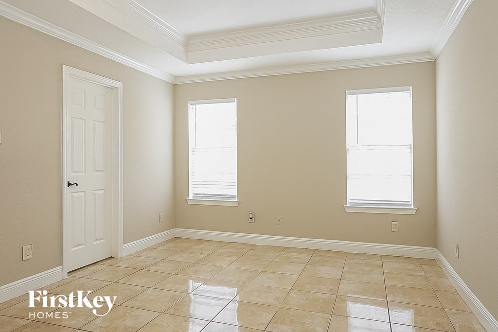 an empty living room with a white door and two windows