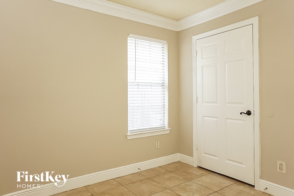 a bedroom with a white door and a window and a tiled floor
