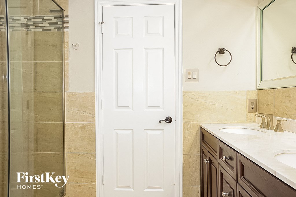 a white door in a bathroom with two sinks and a shower