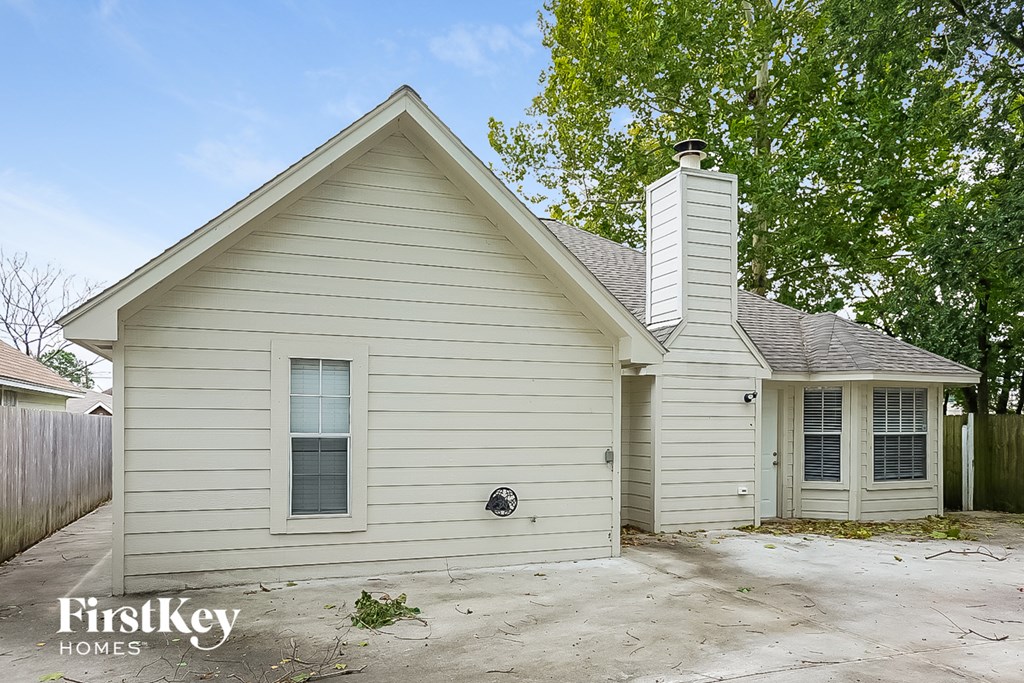 the front of a white house with a driveway and a tree