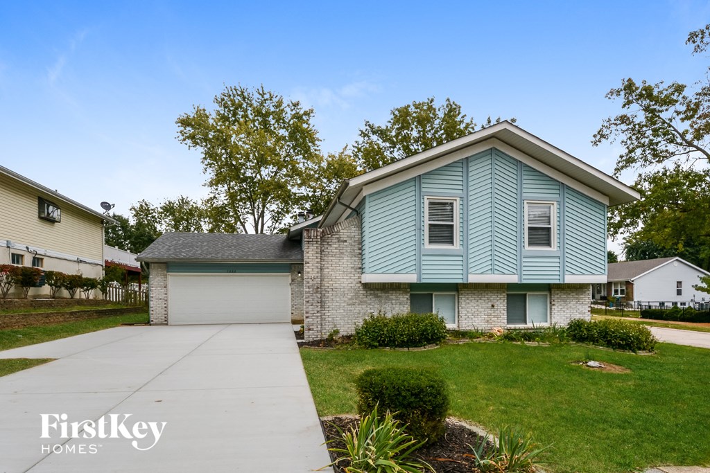 A blue house with a white garage door is for sale.