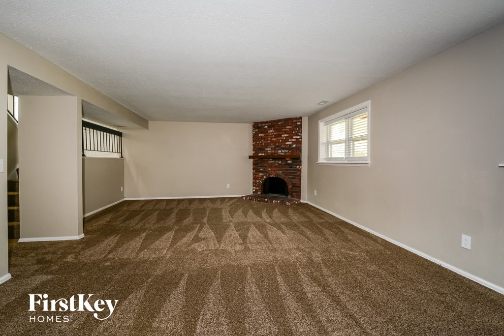 A room with a brick fireplace and a carpeted floor.