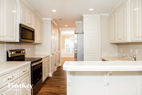 a white kitchen with white cabinets and black appliances