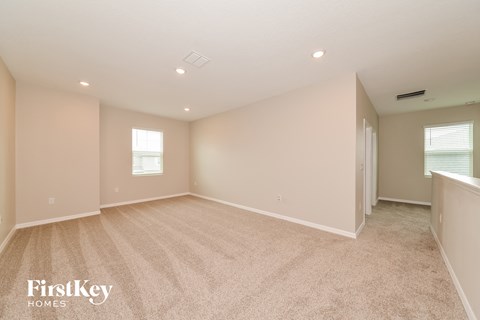 a spacious living room with beige carpet and white walls
