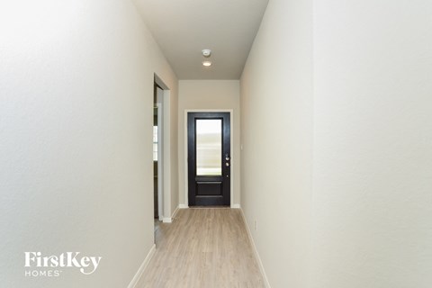 a hallway with white walls and a door to a house