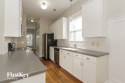 a kitchen with white cabinets and black appliances and a wood floor