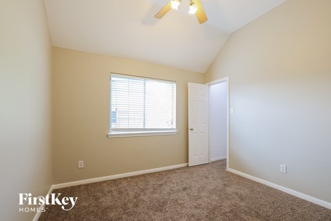 a bedroom with beige carpet and a window and a white door