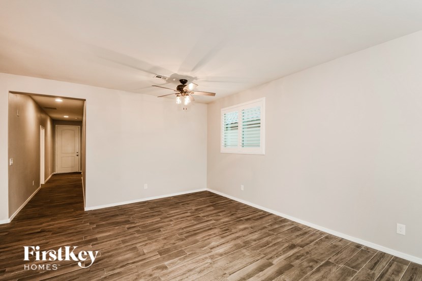 A spacious room with wooden flooring and a ceiling fan.