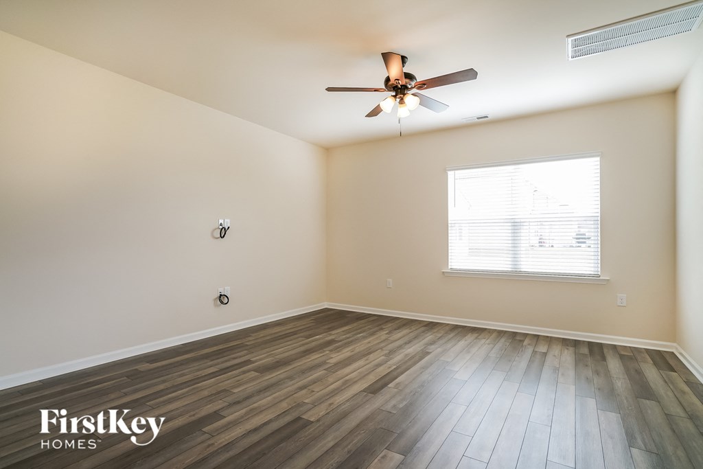 the spacious living room with hardwood floors and a ceiling fan